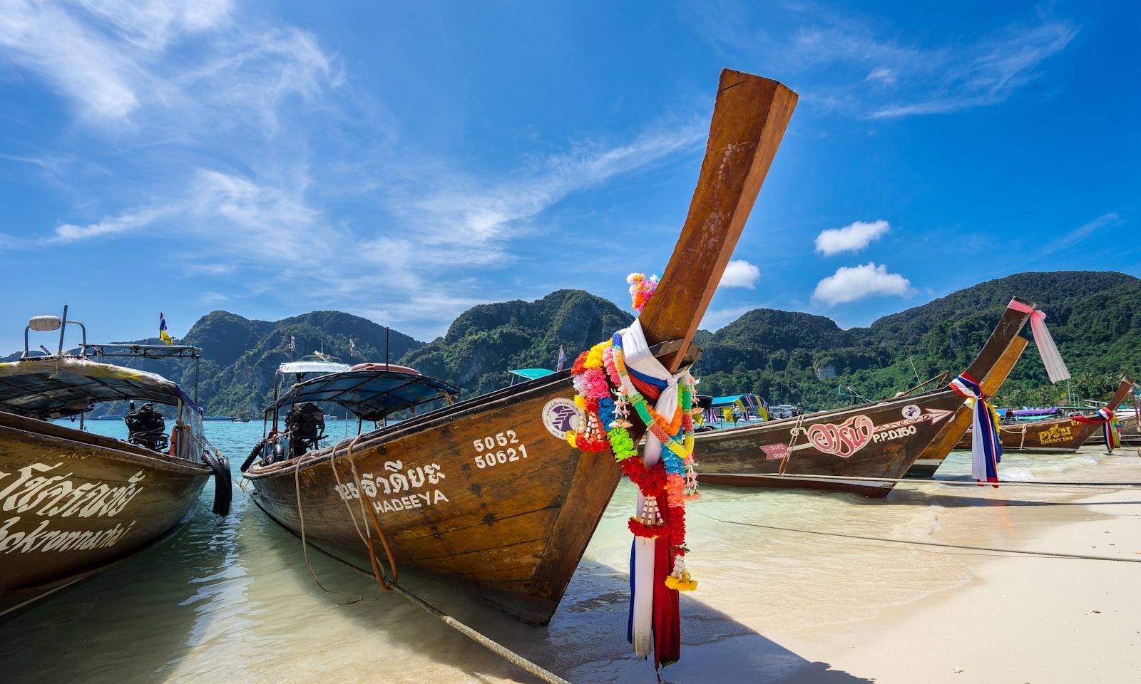 Bows of several wooden longtail boats moored at a Thai beach