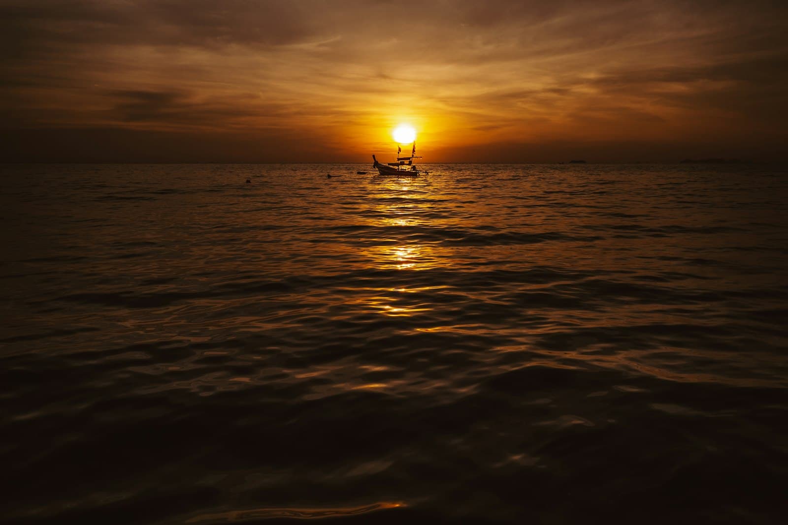 Silhouette of a longtail boat on the water at sunset